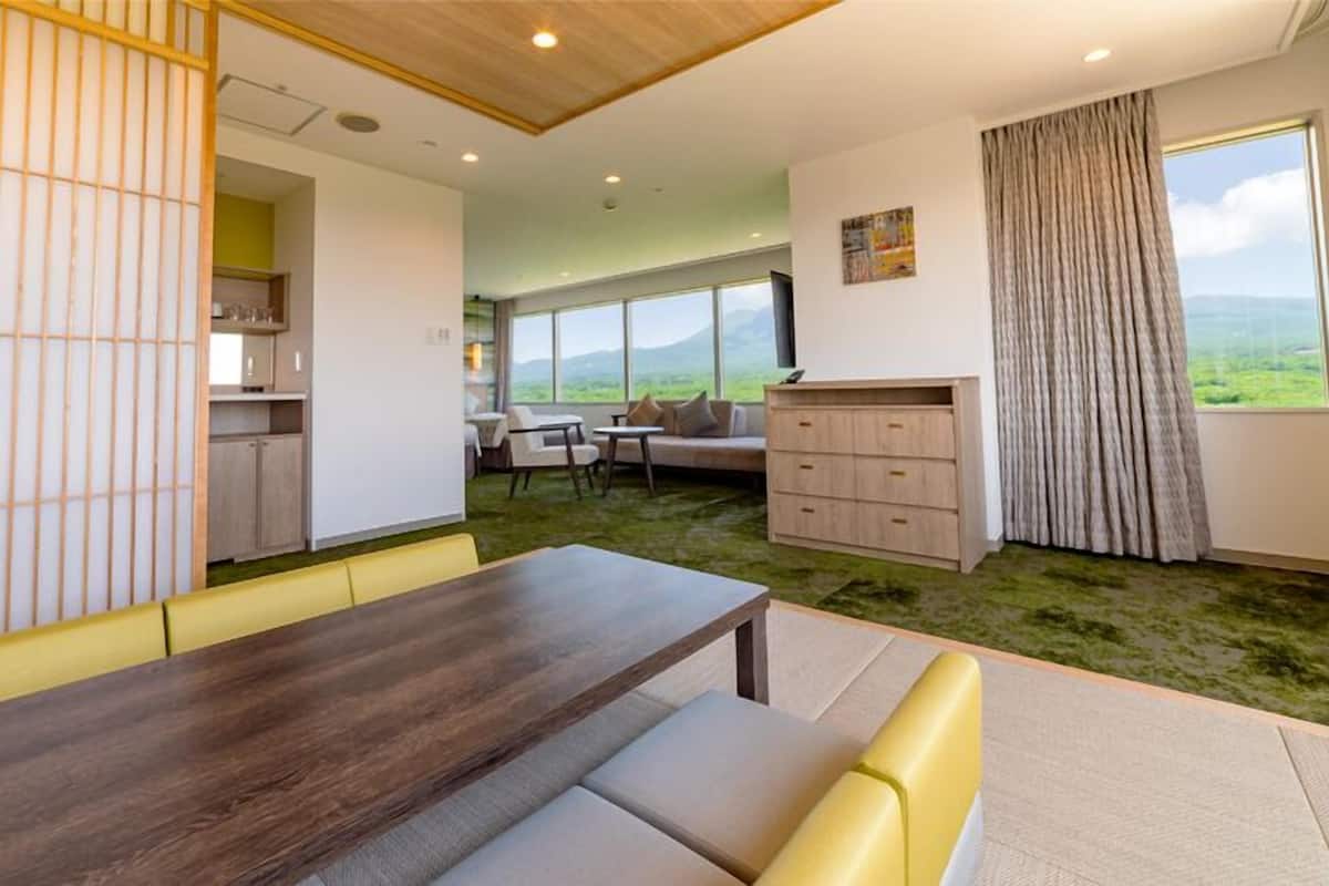 A modern interior with a dining area, a sofa, and a view of the outdoors.