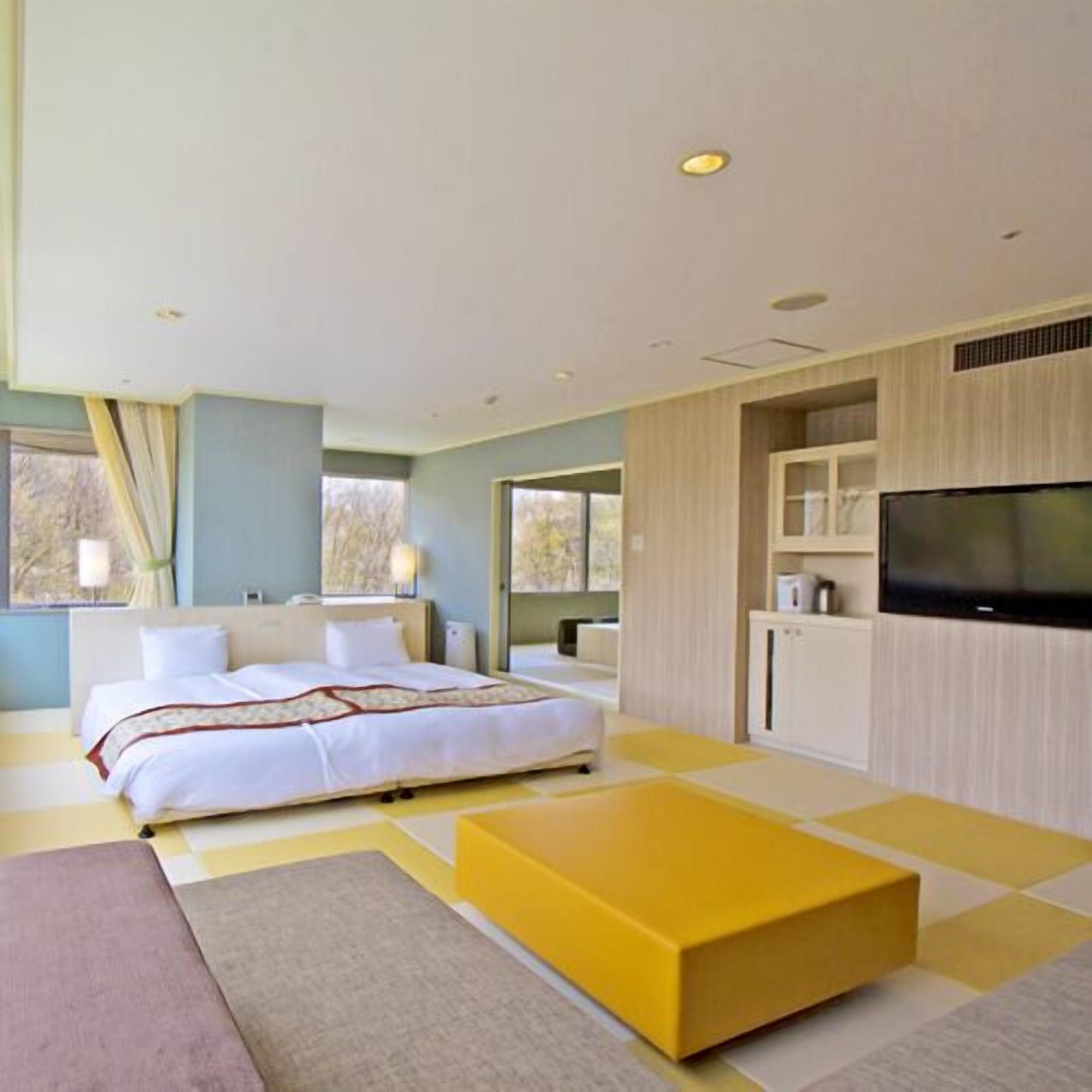 Une chambre d’hôtel moderne équipée d’un lit, d’un téléviseur à écran plat, d’un canapé et d’une table basse.