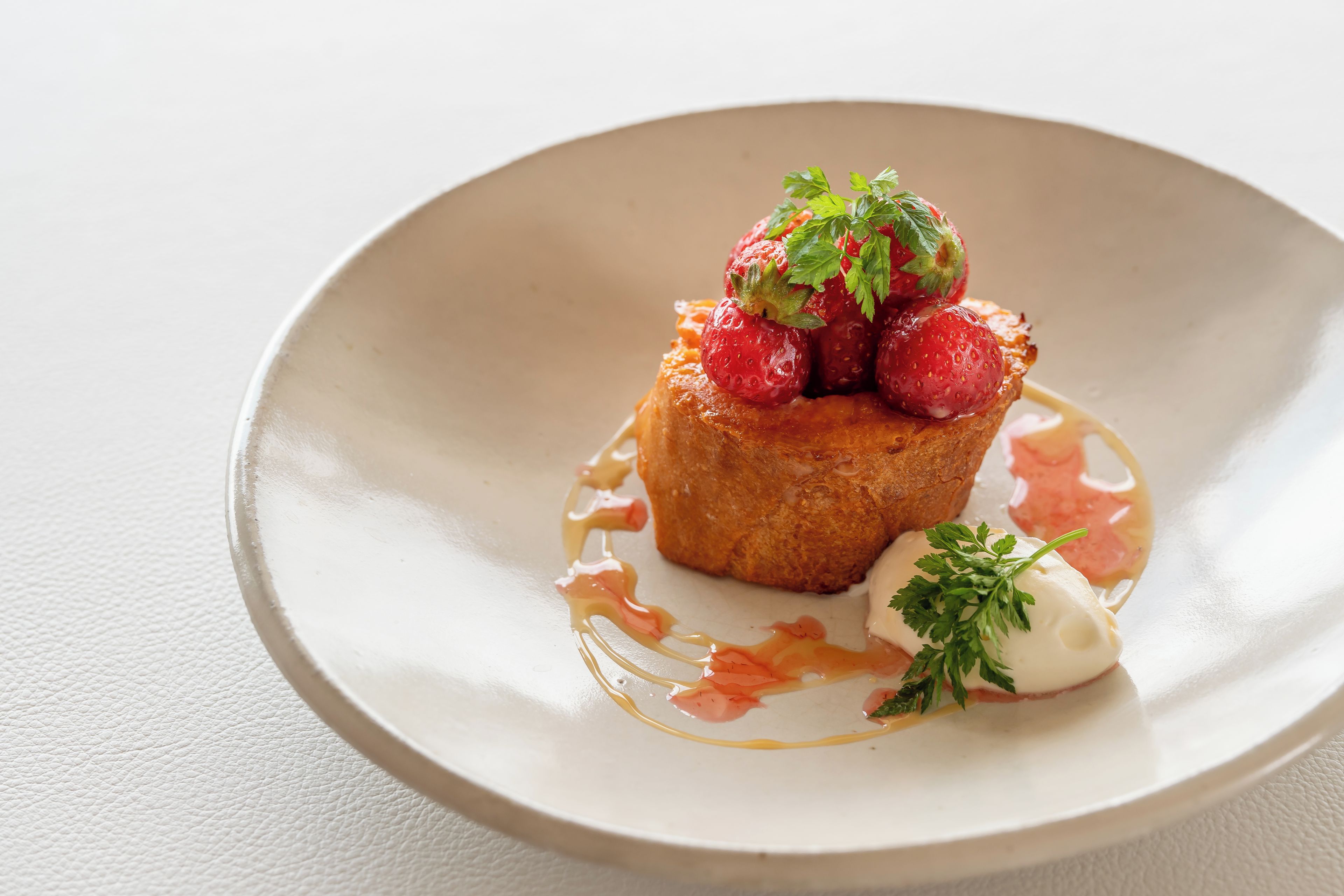 A dessert on a plate with strawberries and a dollop of cream.