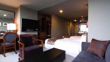 A hotel room with a large bed, a sofa, a TV, and a desk with a chair.
