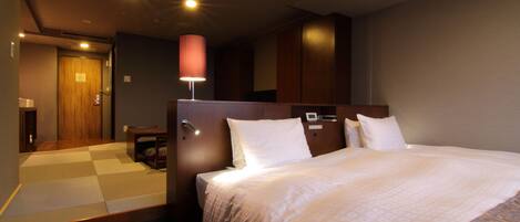 A hotel room with a large bed, a wooden headboard, a bedside table, and a lamp.