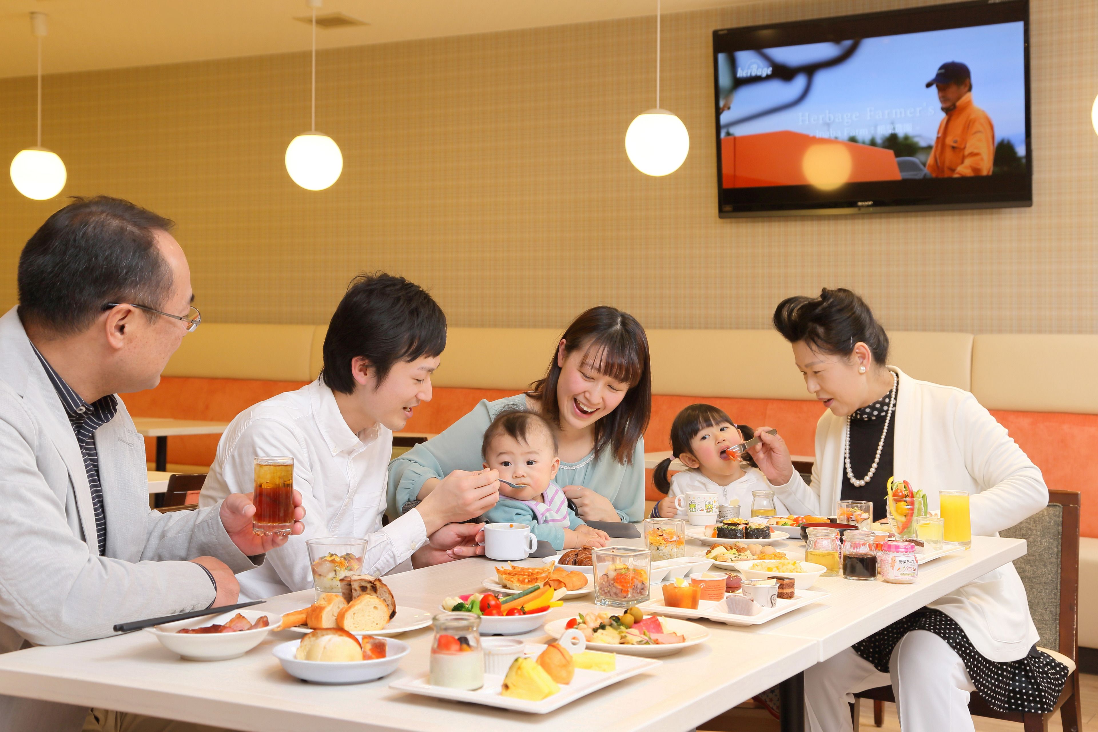 Una familia cenando en un restaurante, con un televisor mostrando un programa al fondo.