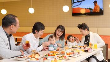 Una familia cenando en un restaurante, con un televisor mostrando un programa al fondo.