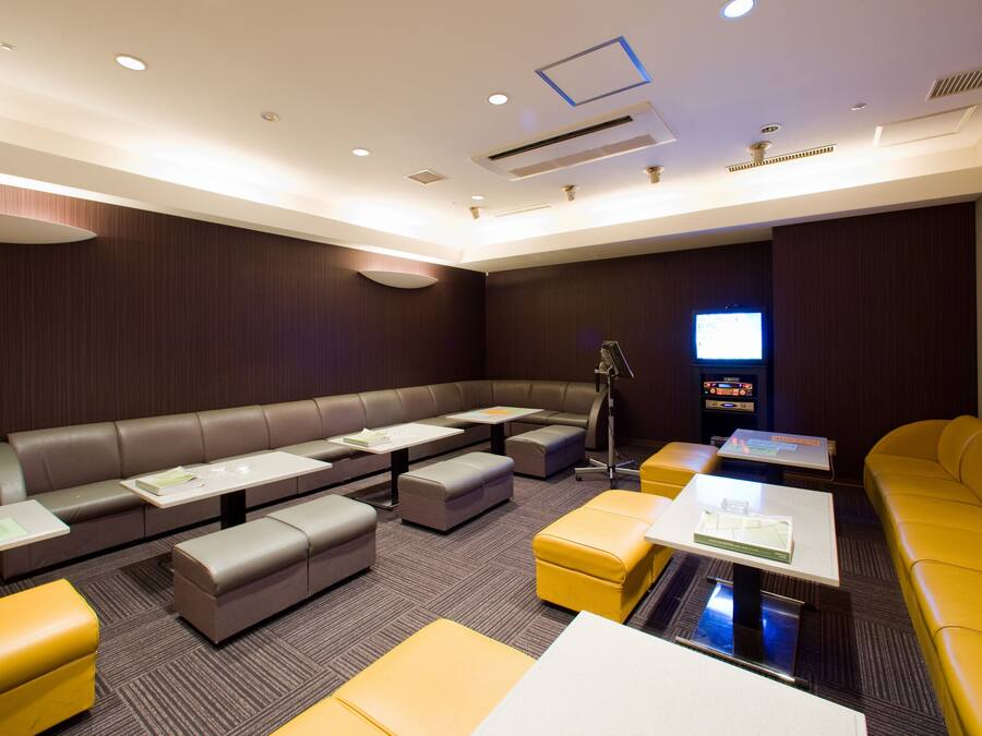 A modern conference room with a large table, multiple seating options, and a television.