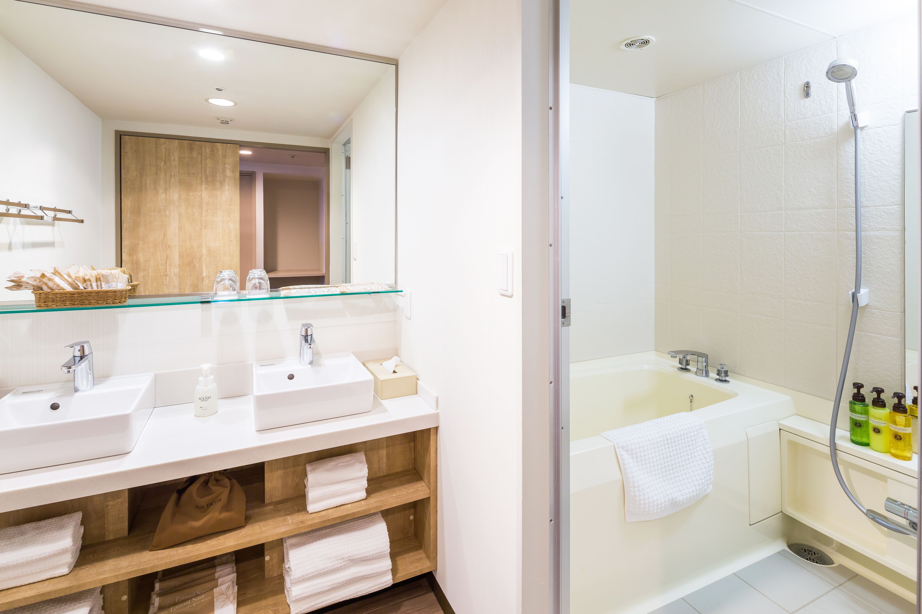 A modern bathroom with two sinks, a large bathtub, and a glass shower enclosure.