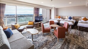 A hotel room with a large window, a sofa, a TV, two beds, and a small table. - Hotel Epinard Nasu (Nasu)