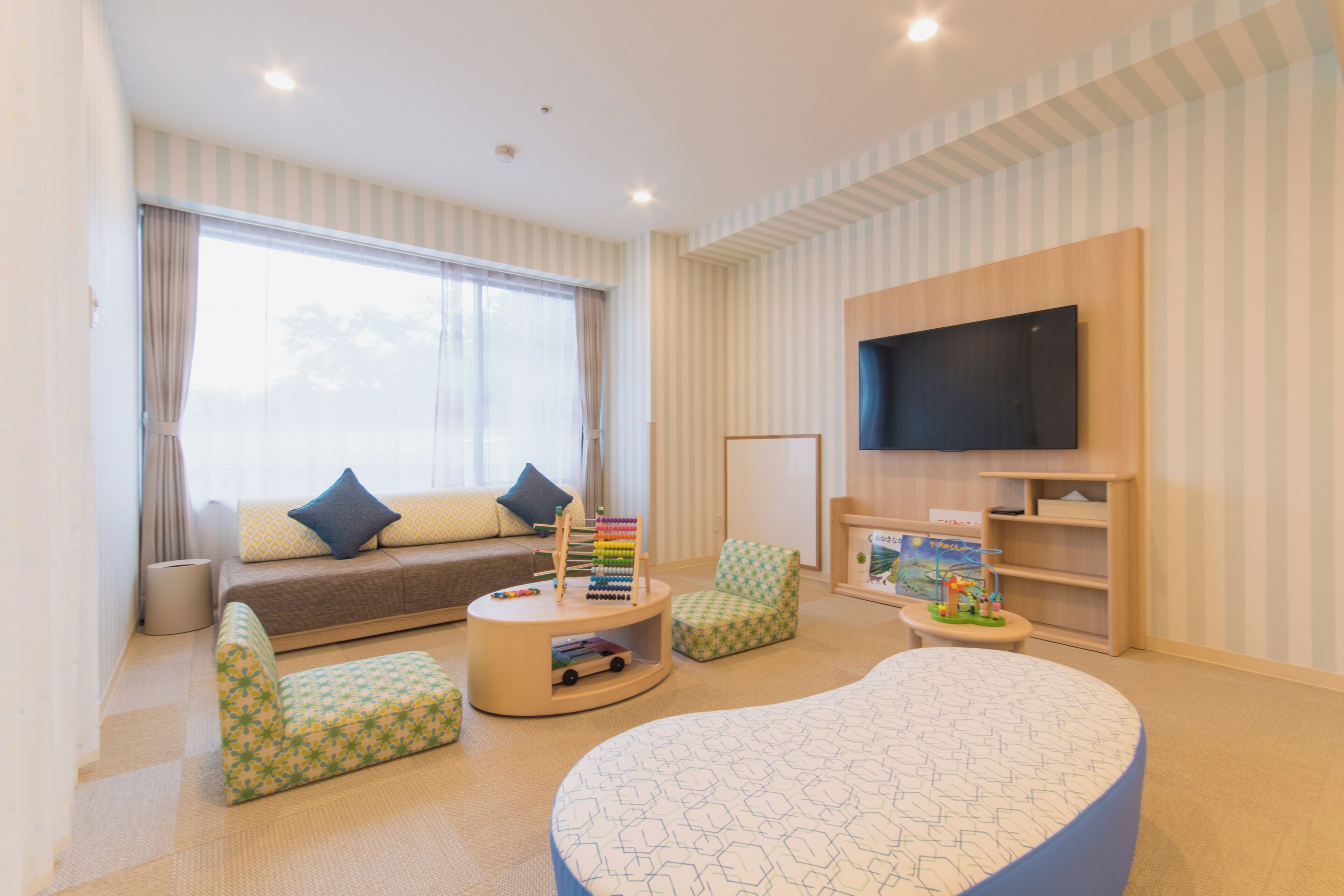 A living room with a sofa, two armchairs, a coffee table, a flat-screen TV, and a bookshelf.