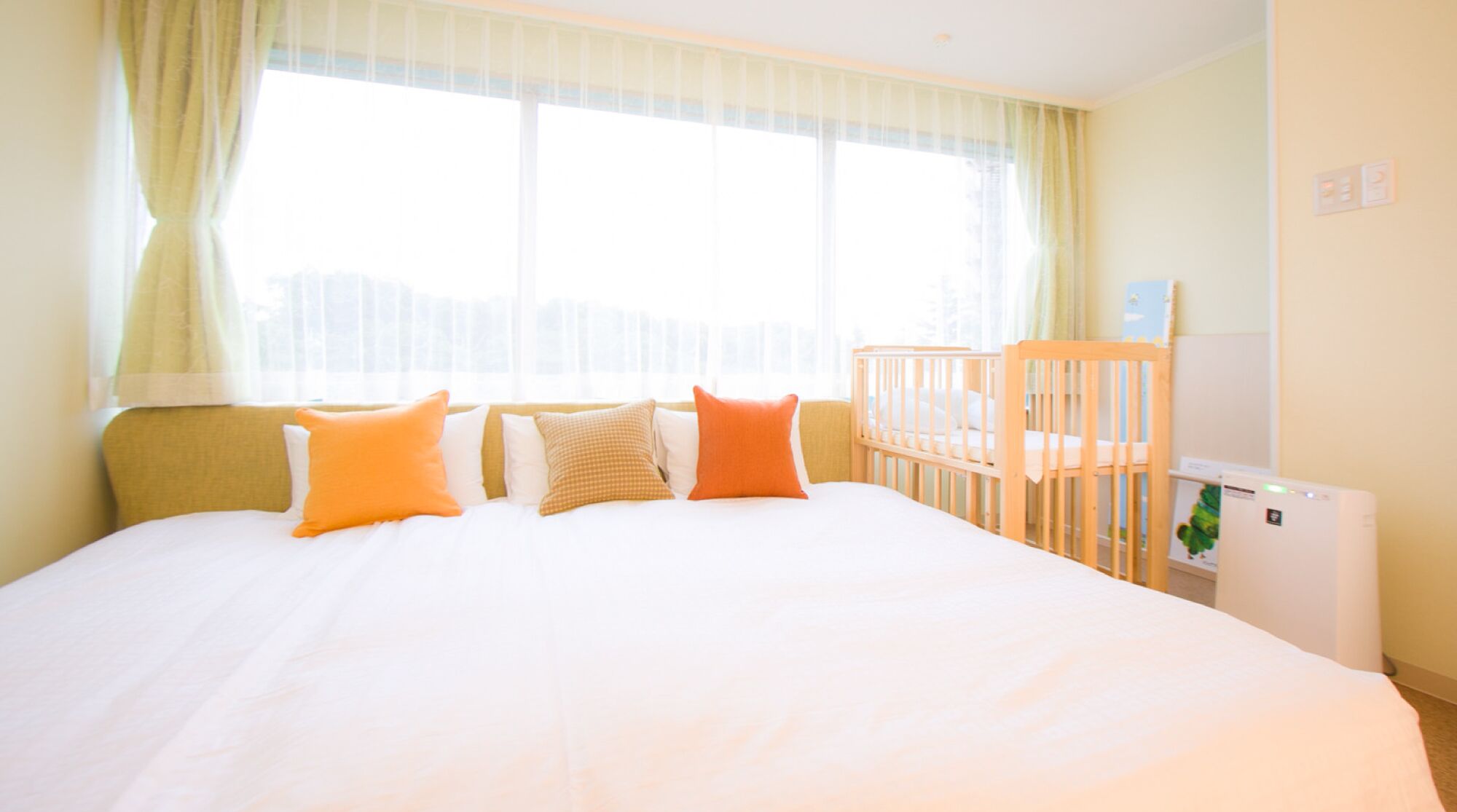 Une chambre d’hôtel avec un grand lit, un berceau et un radiateur.