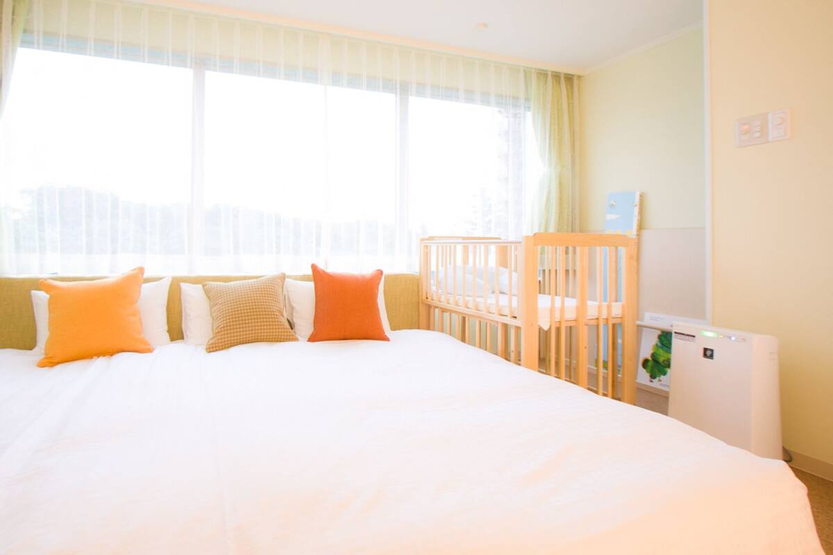 A hotel room with a large bed, a crib, and a radiator.