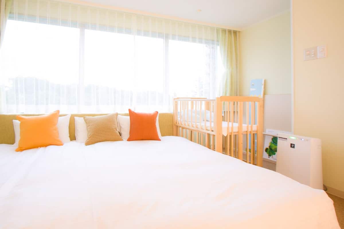 Une chambre d’hôtel avec un grand lit, un berceau et un radiateur.