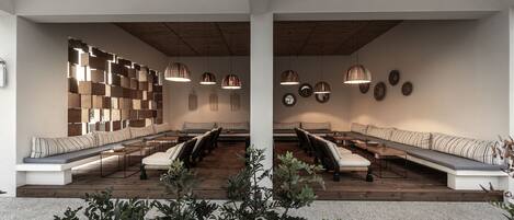 A modern interior with a long bench seating area, wooden flooring, and pendant lighting.