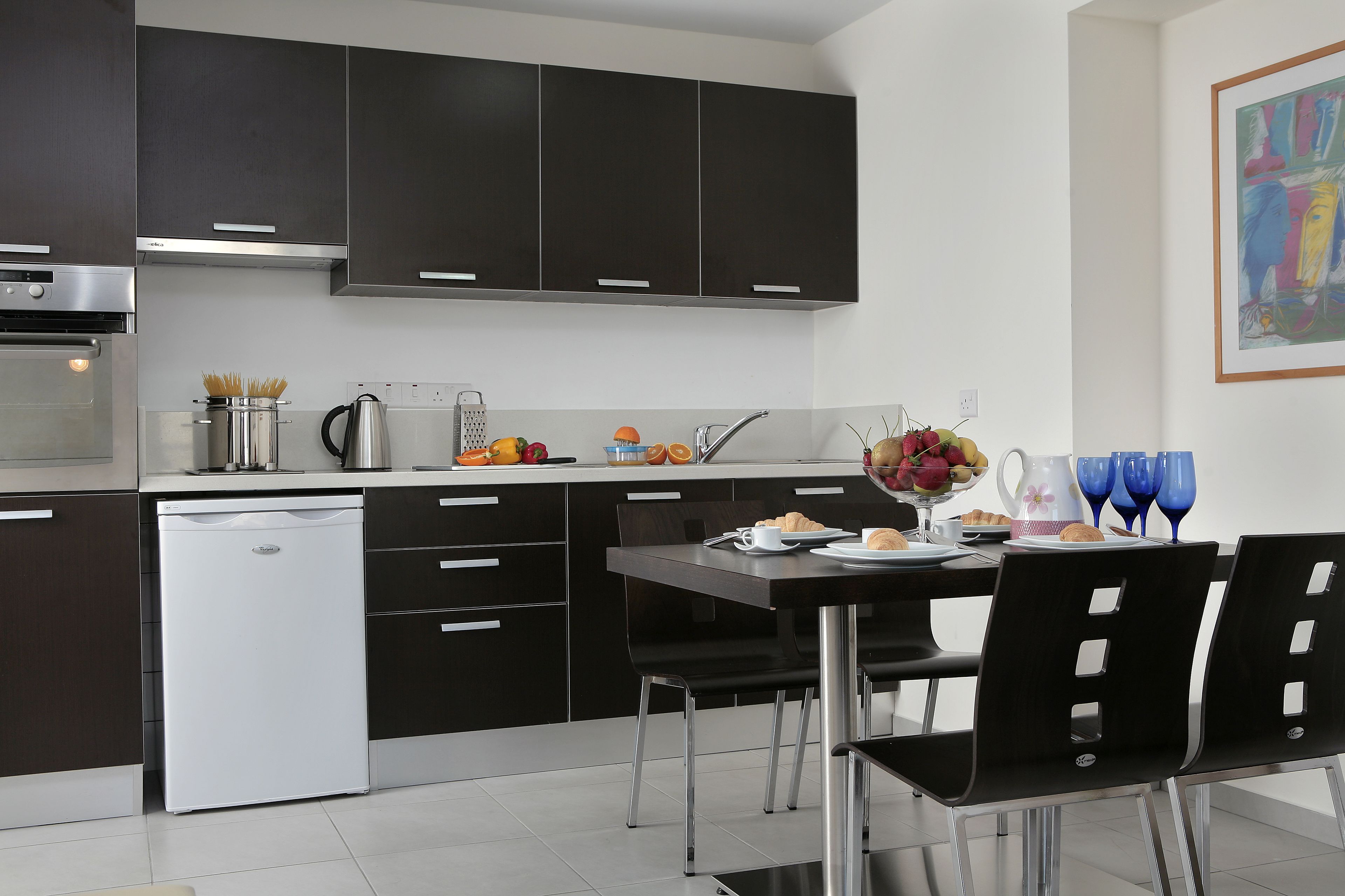 A modern kitchen with dark cabinetry, a built-in oven, and a dishwasher.