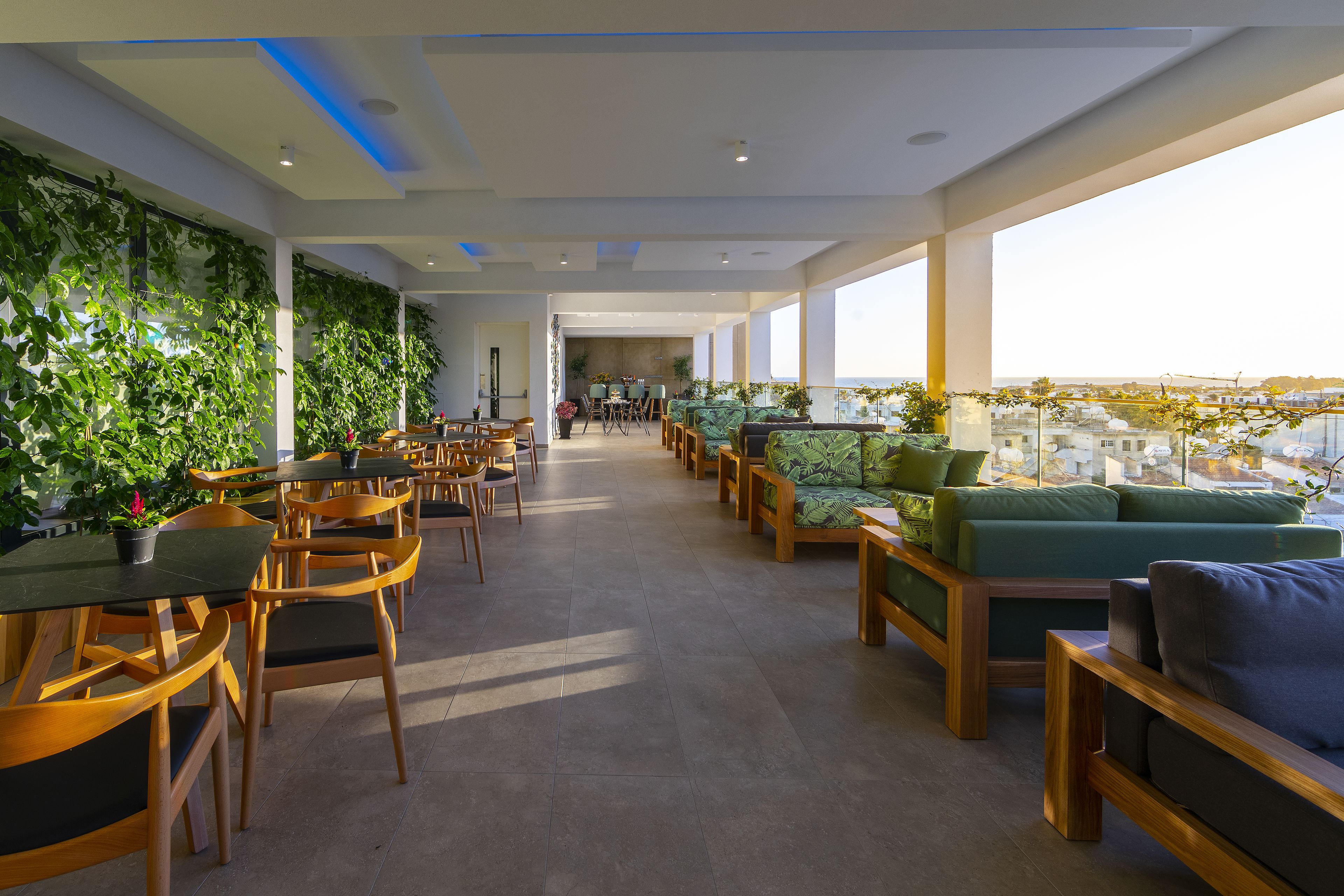 A modern lounge area with wooden furniture, green cushions, and a view of the city.