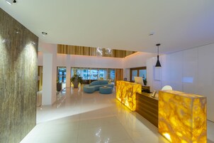 A modern lobby with a marble reception desk, a blue sofa, and a large plant.