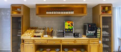 Habitación de hotel con un mostrador buffet de madera, una máquina de café y una selección de botellas de vino.