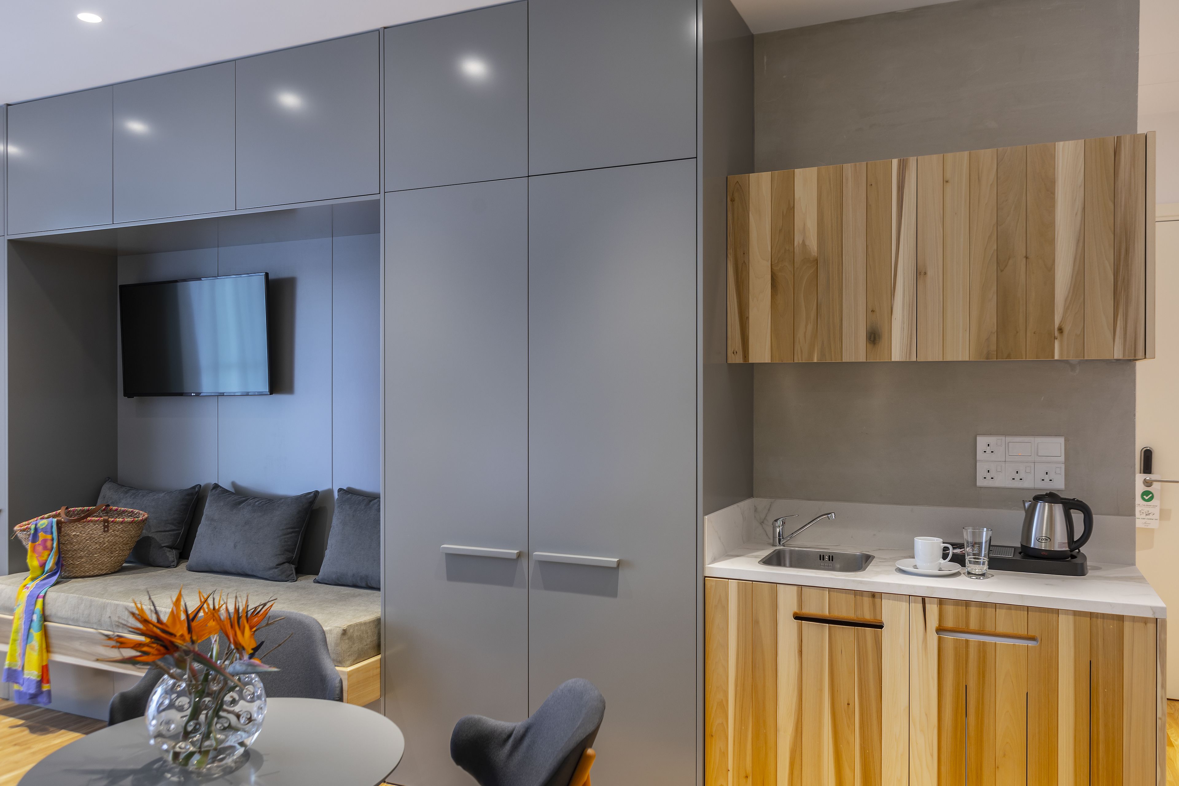 A modern kitchen with grey cabinets, a wooden countertop, and a built-in oven.
