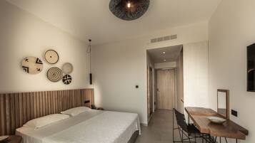 Una habitación de hotel moderna con una cama grande, un escritorio con silla, un espejo y decoración en la pared.