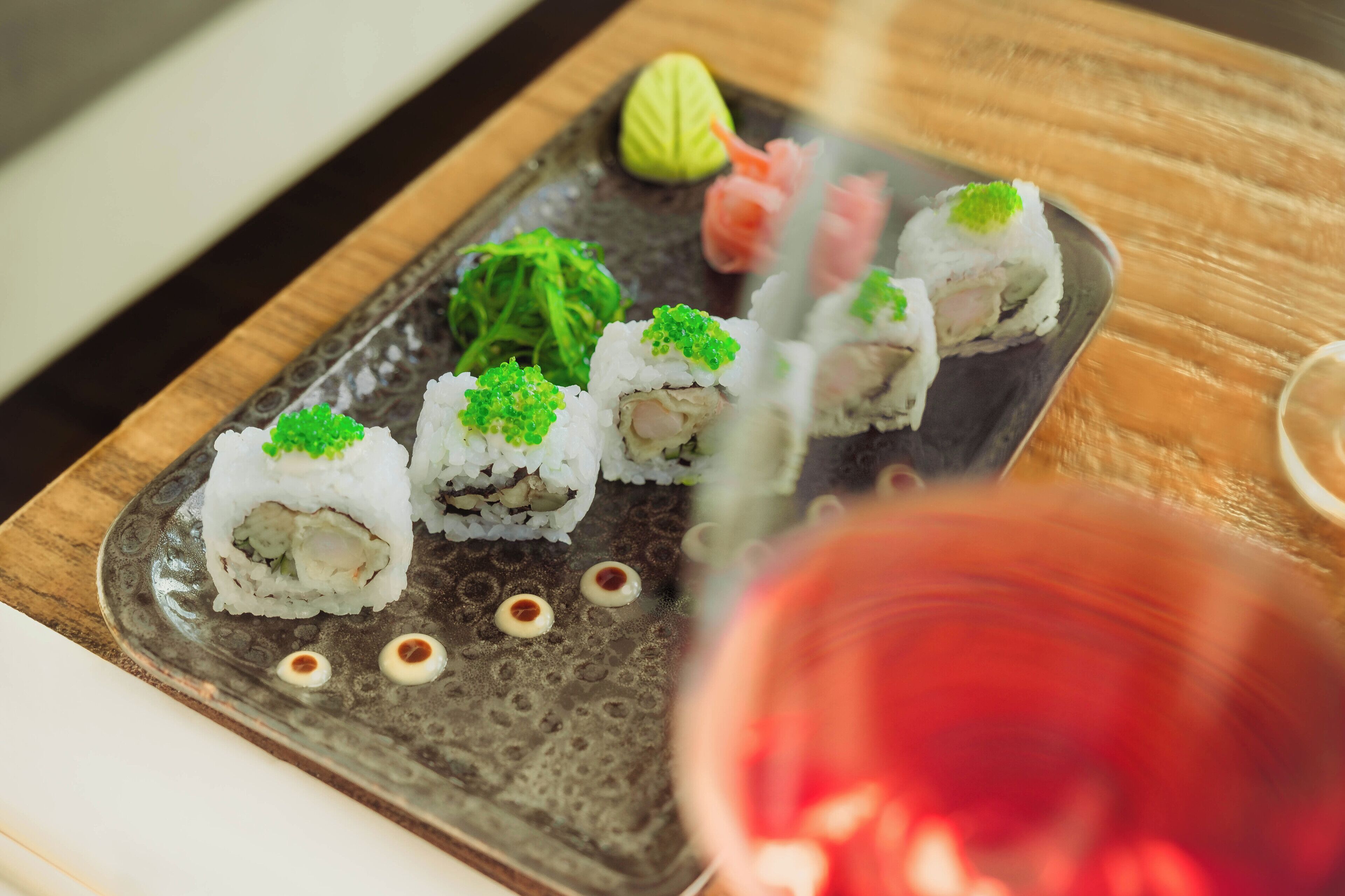 A sushi platter on a ceramic plate with a wooden table.
