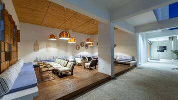 Un interior moderno con techo de madera, zonas de estar e iluminación colgante.