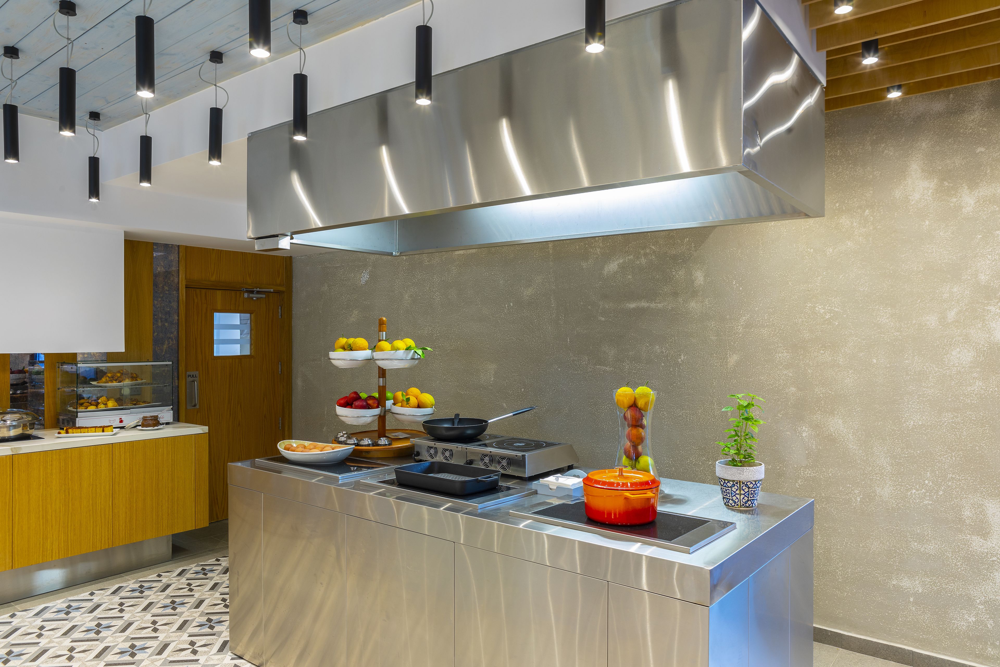 Una cocina moderna con electrodomésticos de acero inoxidable, encimera de madera y una isla grande con estufa y lavaplatos integrados.