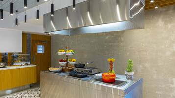 Una cocina moderna con electrodomésticos de acero inoxidable, encimera de madera y una isla grande con estufa y lavaplatos integrados.
