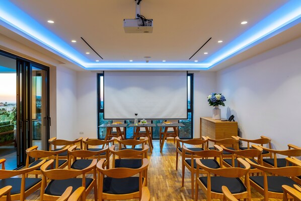 A conference room with wooden chairs, a projector, and a large screen.