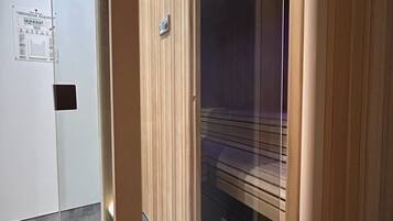 Una habitación con puerta de madera corredera, un separador de vidrio y una lámpara en el techo.