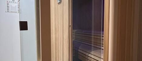 Una habitación con puerta de madera corredera, un separador de vidrio y una lámpara en el techo.