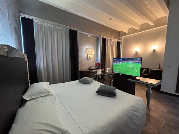 A hotel room with a large bed, a desk, a television, and a mirror. - Daytona Business Hotel (Collecchio)