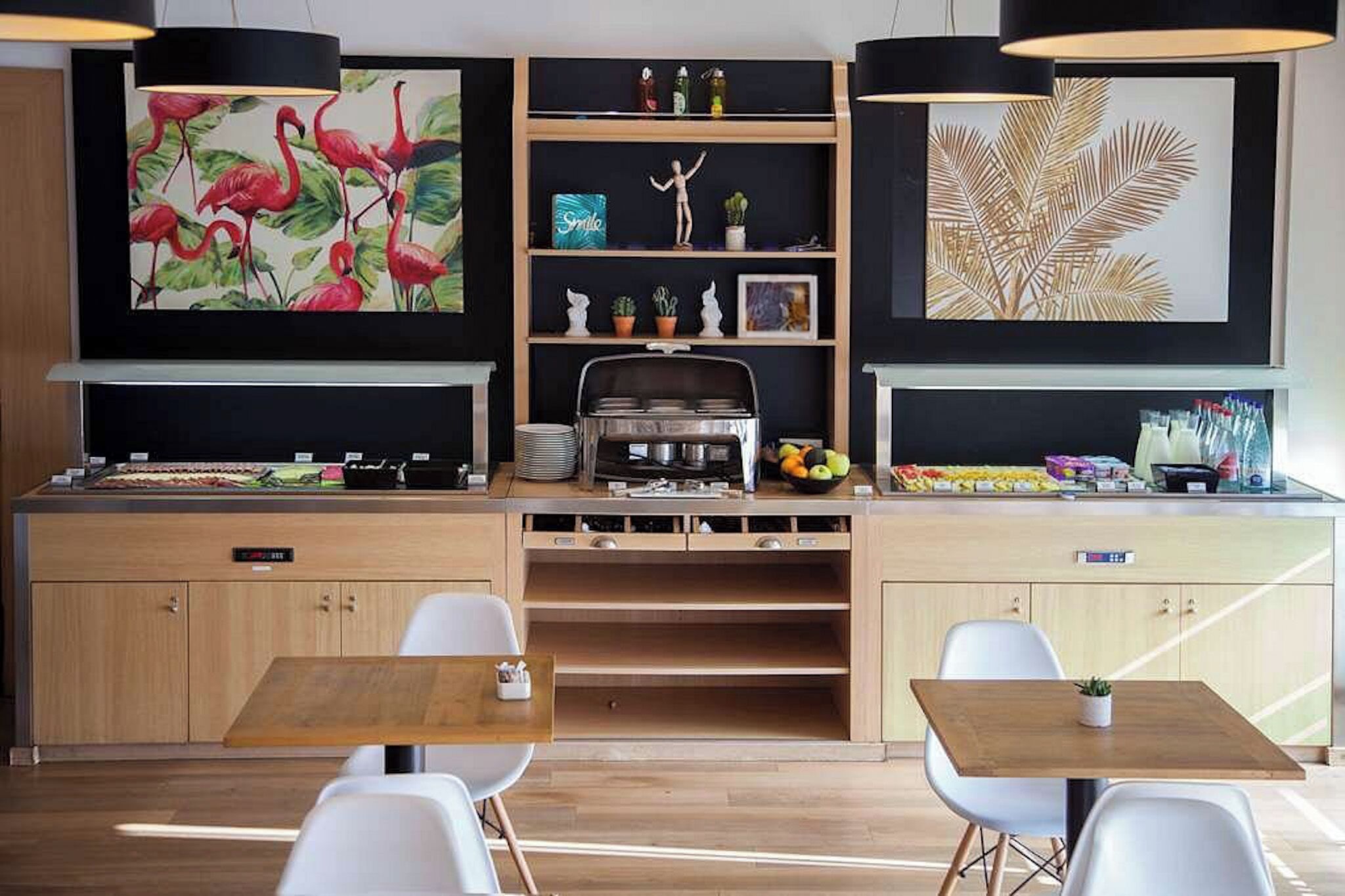 A modern kitchen with a central island, white chairs, and artwork on the walls.