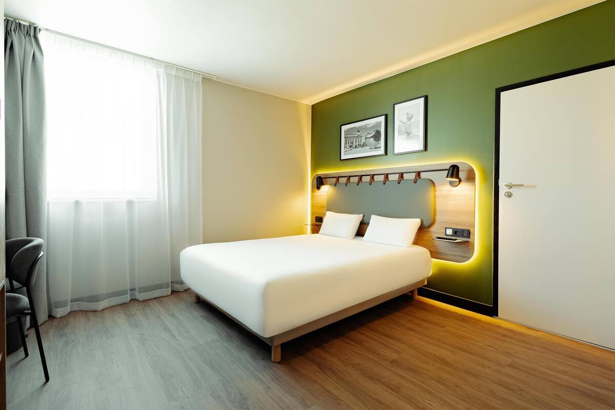 Ein modernes Hotelzimmer mit einem großen Bett, einem Schreibtisch und einem Stuhl.