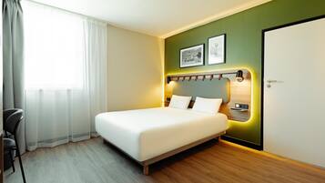Una habitación de hotel moderna con una cama grande, un escritorio y una silla.