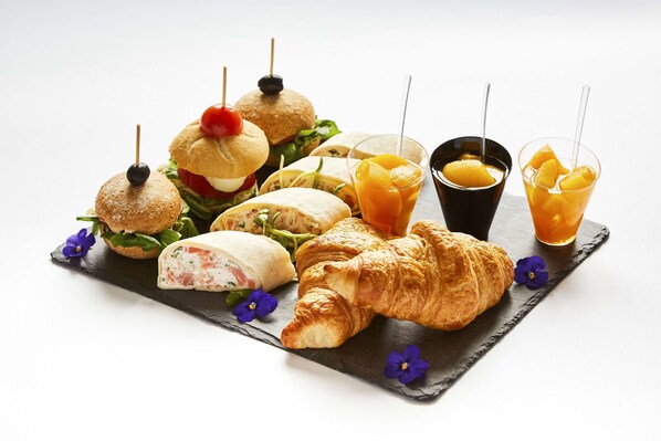 Une variété de sandwichs et de viennoiseries présentés sur une planche d’ardoise sur un fond noir.