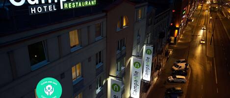 A nighttime cityscape with a hotel sign for Campanile Hotel Restaurant.