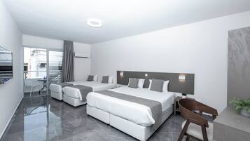Una habitación de hotel moderna con dos camas, una zona de estar y vistas a la ciudad.
