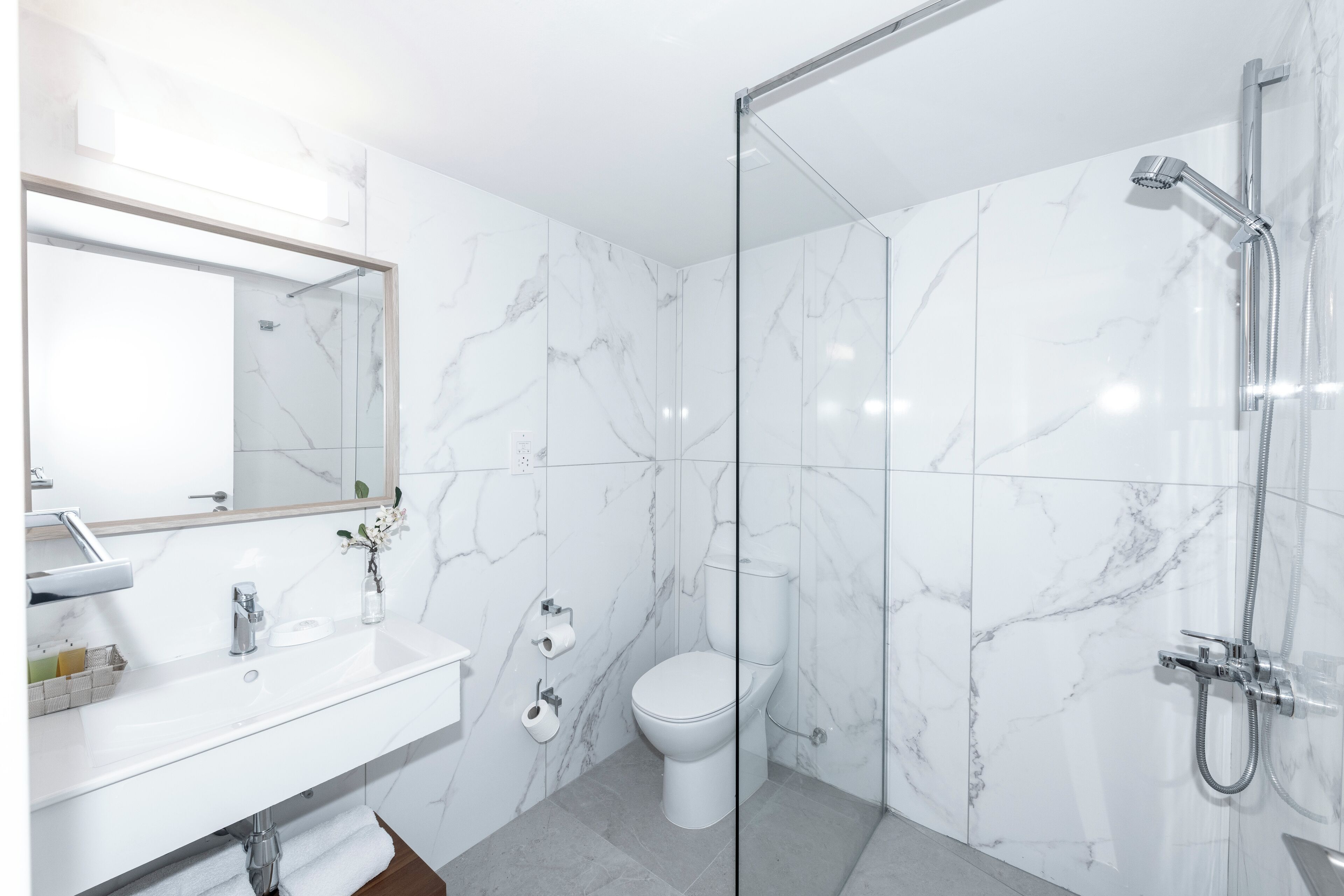 A modern bathroom with a glass-enclosed shower, a white sink, and a toilet.