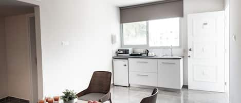 A modern kitchen with white cabinets, a built-in oven, and a window with a view.