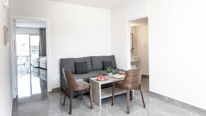 A modern living room with a grey sofa, two wooden chairs, a small table with a plant, and a glass coffee table. - Blazer Residence (Larnaca)
