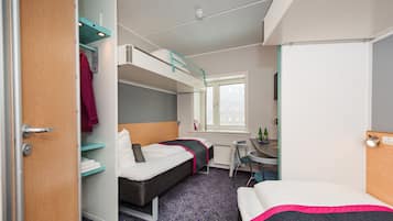 A compact hotel room with bunk beds, a desk, and a small window.