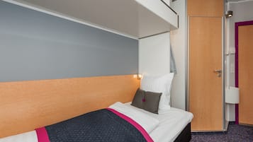 A hotel room with a bed, a wardrobe, and a door.