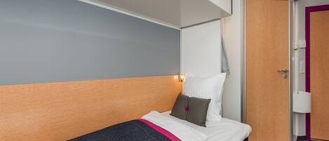 A hotel room with a bed, a wardrobe, and a door.