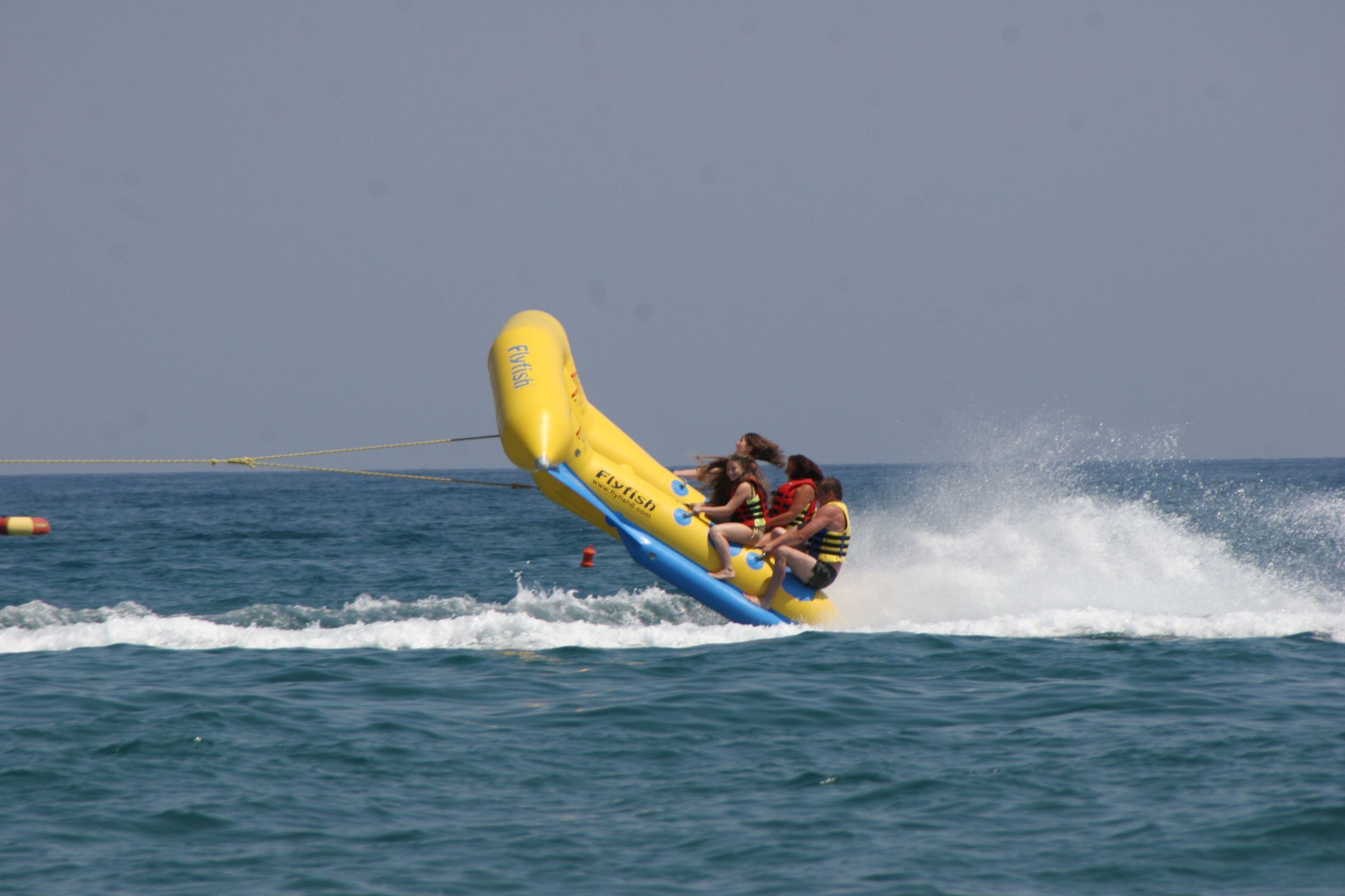 Una embarcación inflable amarilla y azul con gente a bordo que se desplaza sobre el agua.