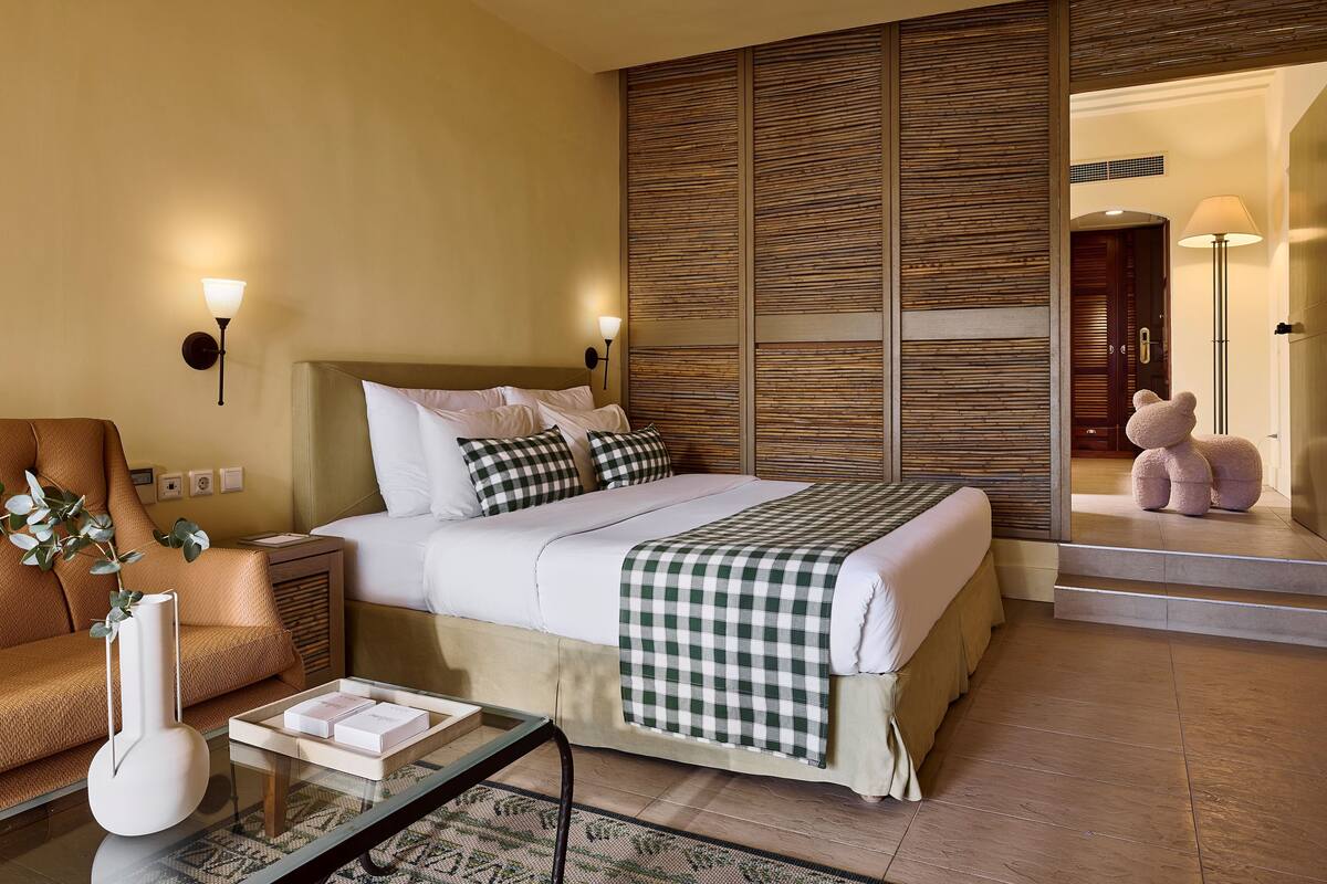 Ein Hotelzimmer mit einem Bett, Nachttischen, einer Couch, einer Lampe und einem Teddybär.