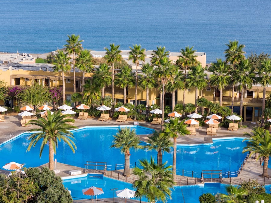 Un resort con varias piscinas, palmeras y vistas a la playa.