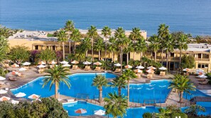 A resort with multiple swimming pools, palm trees, and beach views.