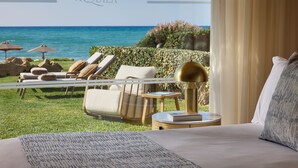 Habitación de hotel con vista al mar, un balcón con sillones de descanso y una cama con vistas.