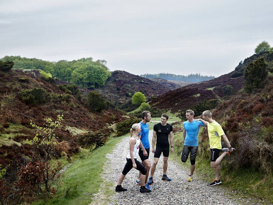 A group of people on a gravel path in a natural setting with hills and trees.