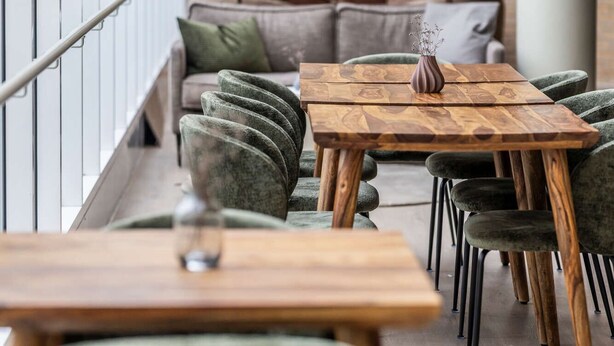 A modern interior with a wooden table and chairs, wicker pendant lights, and a sofa with cushions. - Comwell Rebild Bakker (Skorping)