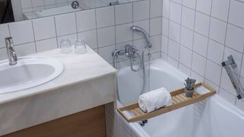 Un baño con lavabo, espejo, ducha y toallero.
