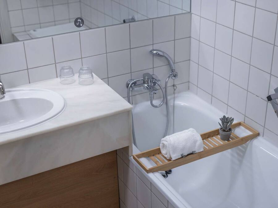 Un baño con lavabo, espejo, ducha y toallero.